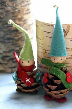 two little gnomes are sitting next to pine cones