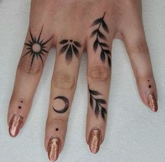 a woman's hand with tattoos on it and two fingers that have different designs