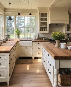 a large kitchen with white cabinets and wooden counter tops in front of an open window