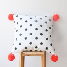 a black and white polka dot pillow with red pom - poms on it