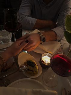 two people sitting at a table with wine and food