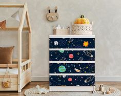 a child's room with a space theme dresser and toy storage bins on the floor