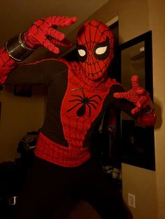 a man in a spiderman costume is posing for the camera with his hands up