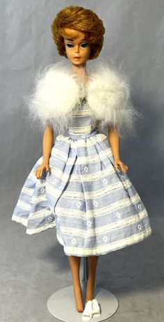 a doll wearing a blue and white striped dress with fur stole around it's neck