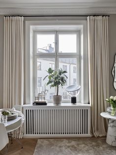 a living room with a radiator, table and chair next to a window