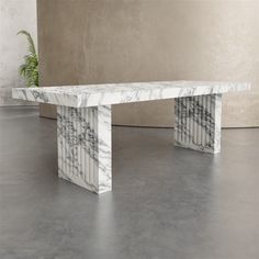 a white marble bench sitting on top of a cement floor next to a planter