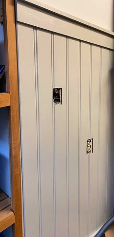 a white locker with two doors and some shelves in the back ground next to it