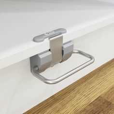 a close up of a metal handle on a white counter with wood flooring in the background