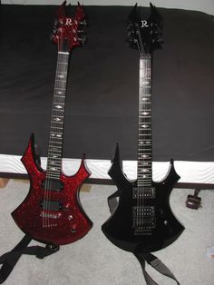 two guitars are sitting on the floor next to each other, one is red and the other is black