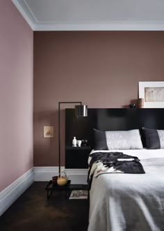 a bedroom with purple walls and white bedding, black headboard and foot board