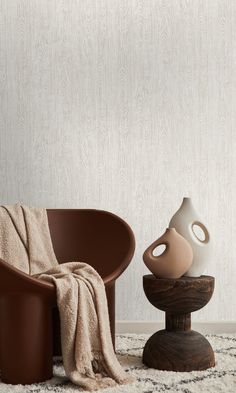 two vases sitting on top of a table next to a chair with a blanket