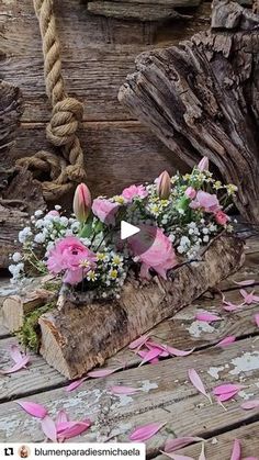 flowers are placed on top of a piece of wood with pink and white petals around it