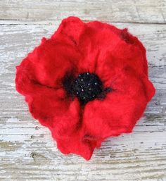 a red flower sitting on top of a wooden table