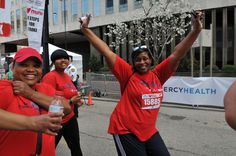 three women in red shirts are holding up their hands and posing for the camera with each other