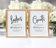 two framed wedding signs on a table with white flowers and greenery in the background