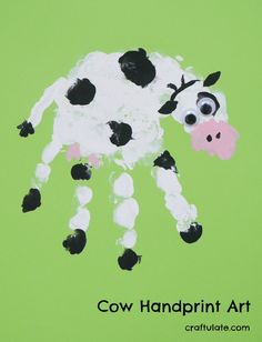 a cow handprint art made with black and white paint on a green paper background