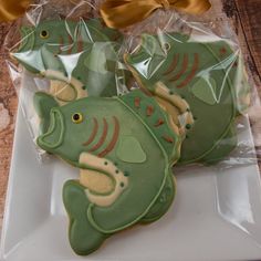 decorated cookies in the shape of fish on a white plate with a yellow bow around it