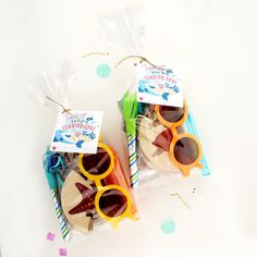 two bags with sunglasses on them sitting next to some confetti and streamers