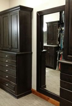 an empty room with two large black dressers and a full length mirror in the corner