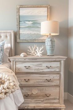 a white dresser sitting next to a bed in a bedroom under a painting on the wall