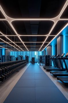 an empty gym with rows of treadmills and blue lights on the ceiling above