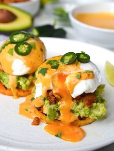 two burritos on a white plate with avocado and sour cream sauce