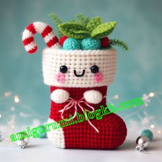 a crocheted christmas stocking with candy canes and holly on top, sitting in front of a blue background