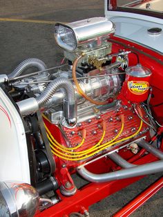 the engine compartment of an old model car is red and white with yellow hoses