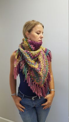 a woman wearing a multicolored crocheted scarf with fringes on her shoulders