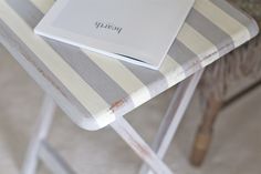 a laptop computer sitting on top of a wooden table next to a striped chair with the word diary written on it