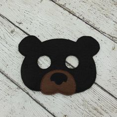 a black and brown bear mask on top of a white wooden floor with text overlay