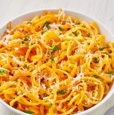 a white bowl filled with pasta covered in parmesan cheese and garnished with parsley