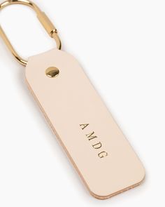 a keychain with the word awg on it is shown in gold lettering