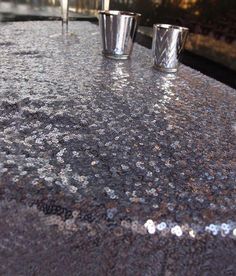 three shot glasses sitting on top of a shiny countertop next to a silver object