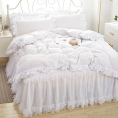 a white bed with ruffled bedspread and pillows