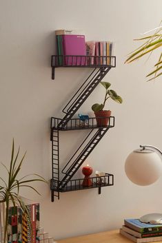 a shelf with books and plants on it next to a wall mounted bookcase in the corner