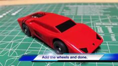 a red toy car sitting on top of a green table next to a piece of paper