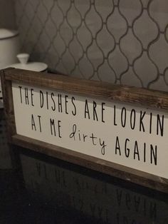 a wooden sign that says the dishes are looking at me dirty again on top of a table