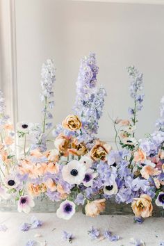 a vase filled with lots of flowers on top of a white table next to a mirror