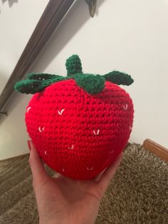 someone is holding up a crocheted strawberry