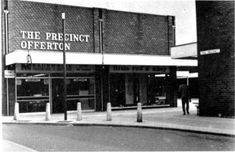 an old black and white photo of the front of a building with people walking by