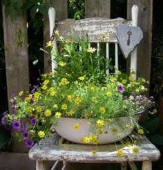 a white bowl filled with flowers sitting on top of a wooden chair