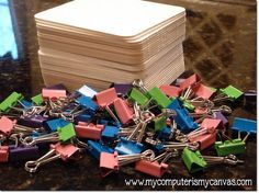 a pile of colorful binders sitting on top of a table next to a box