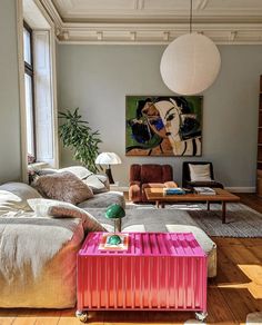 a living room filled with furniture and a painting hanging on the wall above it's windows