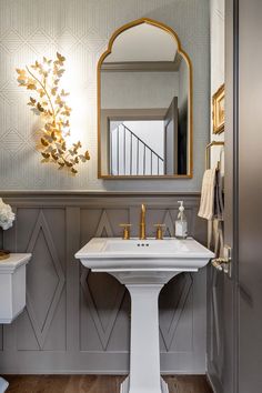 a white pedestal sink sitting under a mirror in a bathroom next to a wall mounted faucet