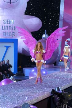 a model walks down the runway with pink wings