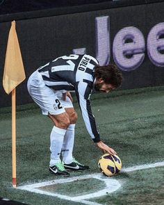 a soccer player bends down to pick up a ball on the field with his hand