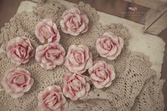 small pink flowers are placed on a lace doily