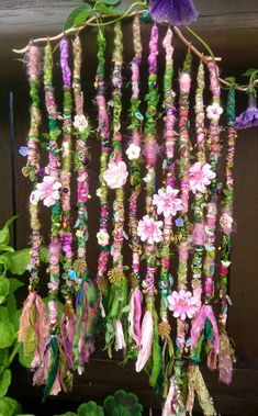 a bunch of beads hanging from the side of a wooden wall next to flowers and leaves