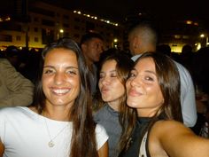 three women are posing for the camera in front of a group of people at an event